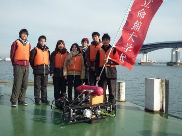 水辺でロボットのフィールド実験に取り組む学生たち